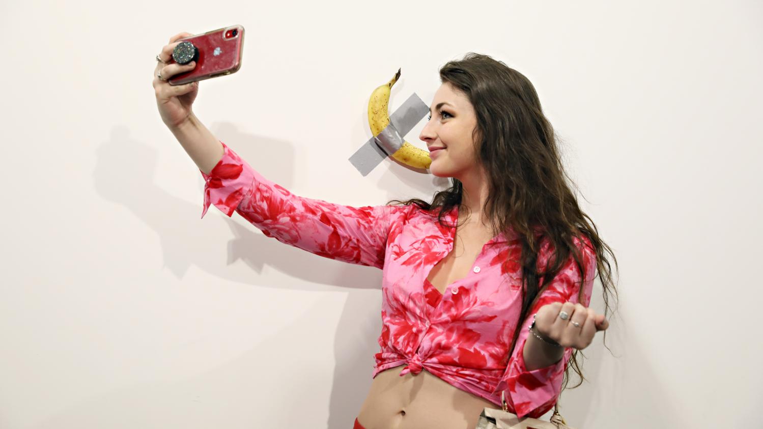 Une jeune femme prend un selfie avec l'oeuvre Une jeune femme prend un selfie avec l'oeuvre
